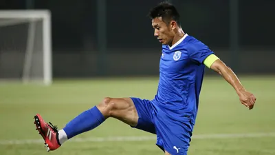 A muscular 25-30 year old male soccer defender in a solid blue jersey and shorts, mid-tackle with his leg extended...
