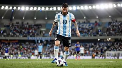 A photo of Lucas Passerini, a 32-year-old Argentine player with a beard, wearing the Belgrano jersey, with a football at...