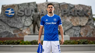 A photorealistic image of a Cruz Azul player, wearing a blue jersey and white shorts, with a determined expression...