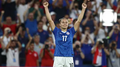 A photorealistic image of a female player in a blue jersey with white shorts, standing with her arms raised in triumph...