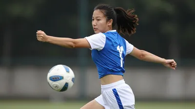 A tight action crop of a young, anonymous female player in a blue jersey with white sleeves and a white number on the...