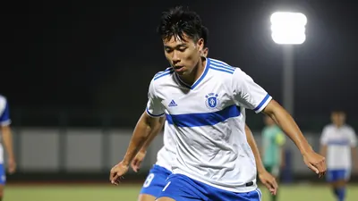A 26-year-old midfielder in a white jersey with a blue stripe and blue shorts, playing a one-on-one with an opponent...