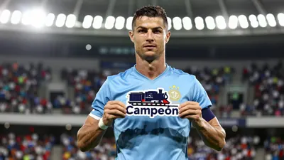 A muscular male soccer player in his mid-20s, wearing a solid light blue jersey with smooth fabric, stands in front of a...