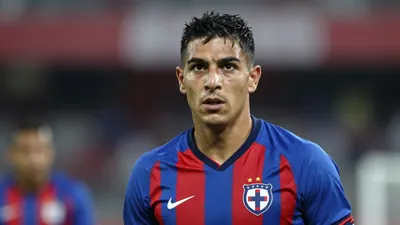 Mid-30s muscular Cruz Azul defender, head-and-shoulders, eyes sharp, wearing the blue-red home jersey with the club crest...